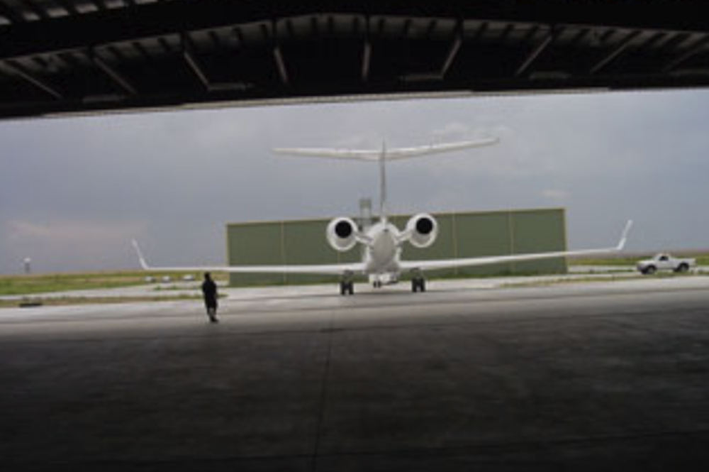 Private jet in hangar with person approaching outside.